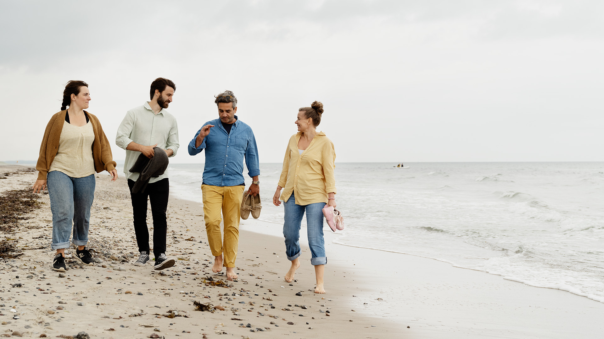 Venner går en tur på stranden, hvor rejseforsikringen også gælder.